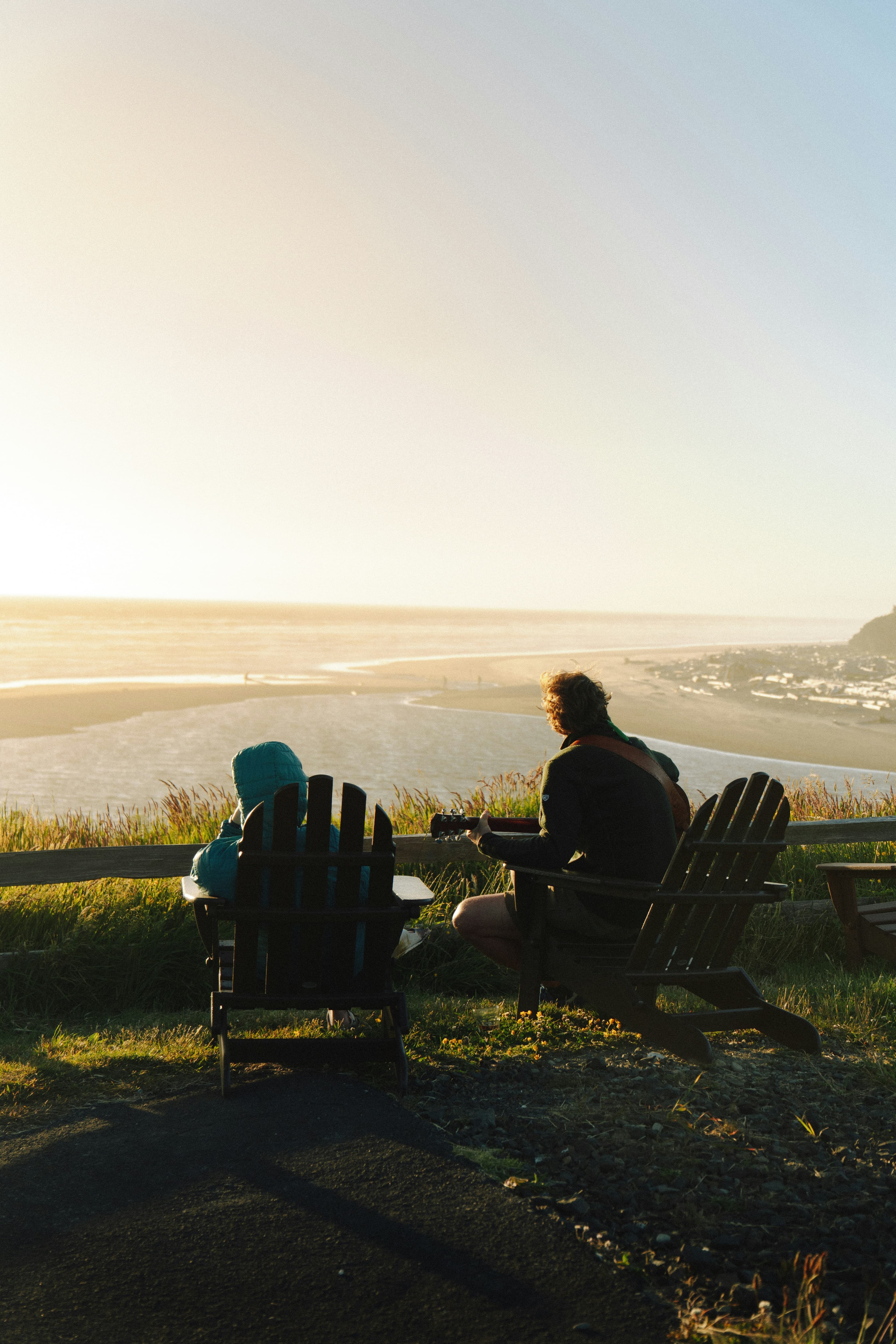 Two people sitting on deck chairs looking out at the ocean
